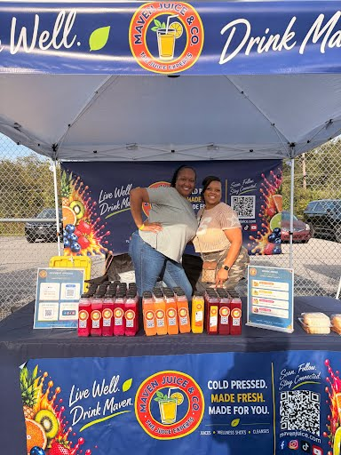 Maven Juice homecoming setup showing the branded tent, backdrop, tablecloth, juice lineup, and tabletop signage